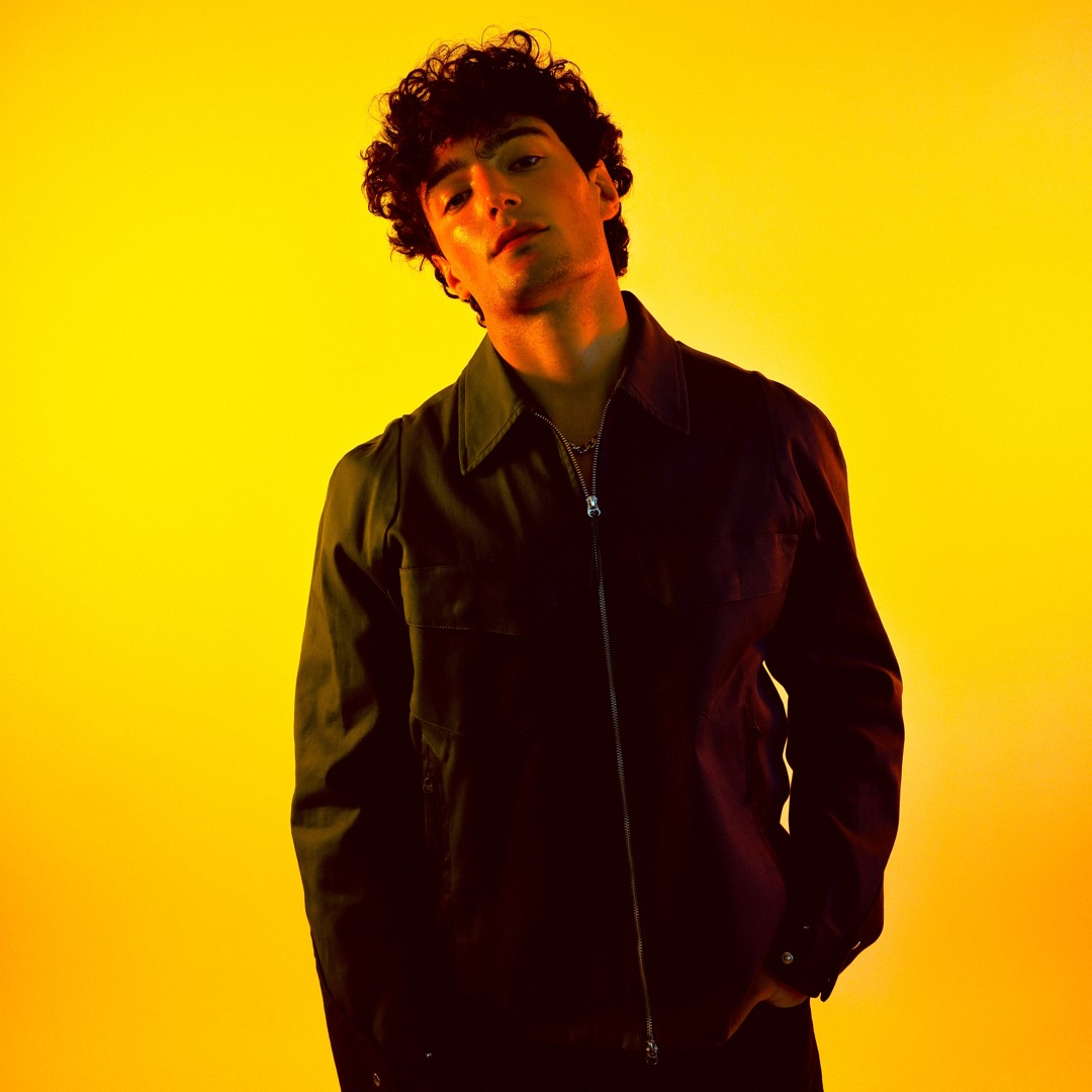 Gavin Blac in a dark jacket against a yellow background